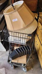 lot 223 image: SHOPPING CART WITH CONTENTS INCLUDING LAMP SHADES, BED RISERS, AND MORE AS SHOWN.