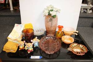 lot 61 image: Orange and iridescent dishes (some are Fire King Anchor Hocking), yellow cloth napkins, ceramic mice