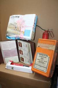 lot 138 image: Gas mask, unopened Moen faucet, oil can Delta flush lever, and Gold replica stamp collection