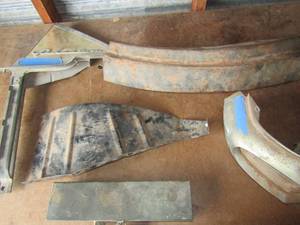 lot 123 image: Pieces to a compression gauge, 1956-57 ford thunderbird front fender splash shield, ford headlight part number # BJ-8207-A, p-77L schofied panel, some sort of part for a phaeton