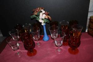 lot 112 image: Amber Thumbprint and Green Mist Crystal Wine and Water glasses and small blue vase with floral arrangment