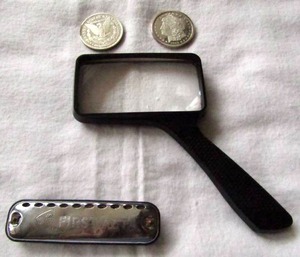 lot 124 image: Morgan dollars (Replicas not silver), Vintage First act harmonica, magnifying glass