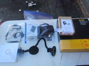 lot 32 image: Plantronics Blue tooth ear bud new, Phone holders for car. Truck, Canon power shot camera, Apple Watch charger plate used