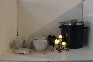 lot 42 image: Large Stock Pot with Steamer Basket, White Soup Bowls and Matching Mugs, Stainless Steele Ladel, Metal Candle holder with LED Candles, Clear Glass Heavy Square with pincones, and Slicer toold