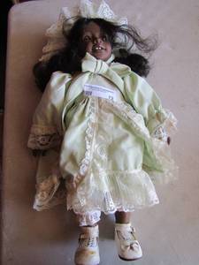 lot 72 image: Heidi Ott brown skin doll wearing a green dress with white dress shoes,also has a hat that matches the dress