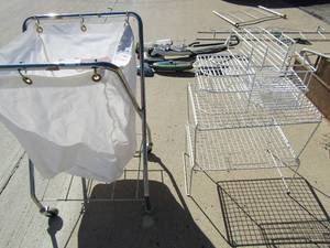 lot 31 image: white callapsable with laundry bag holder on 4 wheels, shampoo and shower holder x 3 and a 2 tier white wire shelf