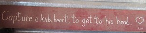 lot 118 image: wooden wall art 7x48 caption says  capture a kids heart, to get to his head