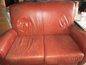 lot 123 image: Broyhill off red lovew seat leather with high wooden feet, has a few scratches from what appears to be a cat kitten