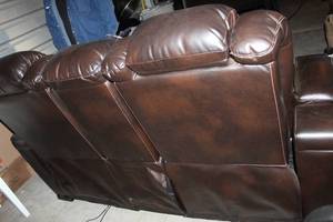 lot 295 image: Two Person Reclining Loveseat, leather made by Ashley, has all the bells and whistles, ... Electric recliner, cup holders, Arm rest storage, and more,  see photos approximately 72 inches long