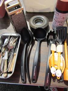 lot 45 image: New wine glass in cover, New set of KitchenAid serving pieces qty 5, small pan of misc. kitchen utensils, Mini tire coaster qty 1