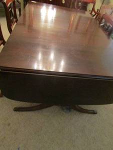 lot 25 image: Solid cherry wood dining table, with 3 music symbol stands under it- both ends fold down and back up for more space, size with to ends down 296642-- with ends up 298ft 242-- each leaf is 12 wide qty 3