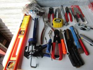 lot 306 image: Tool lot includes, cable crimpers NIP, plyers, screw drivers, cocking gun, hand level, safety goggles and more