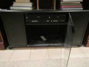 lot 1160 image: black rolling TV table with glass front doors 18x35x19, also comes with a Magnavox dvd vs. player
