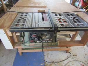 lot 204 image: wooden work shop table has a delta 10 in bench saw attached size 38in x 73in x 48 in