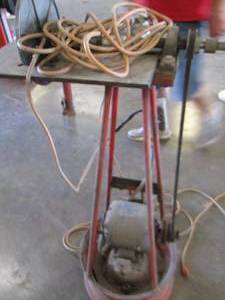 lot 24 image: GRINDER WIRE BRUSH SET UP W singer sewing motor welded onto a tire rim STAND