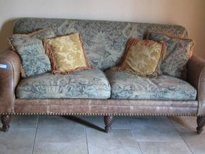 lot 3 image: TAN LEATHER COUCH HAS GREEN FLORAL CUSIONS AND 4 DECORATIVE PILLOWS