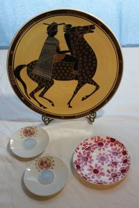 lot 180 image: Two (2) Saucers The Suiter Bonnie and Neil Dessert Plate 12 Wall Plate Doric Hande Made in Greece Numbers with Brass Plate Stand