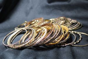 lot 217 image: (60) GOLD TONE metal, aluminum, and plastic bangle bracelets. Assorted styles.