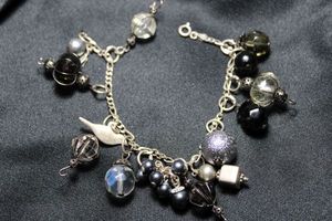 lot 23 image: Sterling Silver Italian charm bracelet with caged glass dangles and other charms. Marked 925 and Ital on clasp fastener. 7.25L. Charms unmarked. Spring ring clasp.