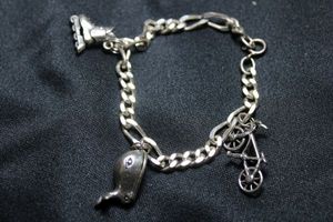 lot 152 image: Sterling Silver Figaro link 7L bracelet with sterling charms including articulated Moby Dick whale with fisherman inside, bicycle and roller skate. Bracelet marked 925 on clasp, all 3 charms are marked Ster or 925. 21.6 gr approx