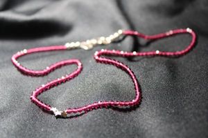 lot 12 image: Sterling Silver faceted ruby glass bead necklace with (3) sterling station beads in star form and an unusual heart shaped clasp. Clasp and stars all marked 925.17L
