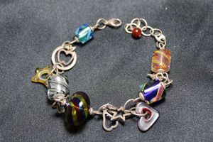 lot 45 image: Sterling silver 9L charm bracelet with Venetian or Czech glass beads and dangles. Marked 925 on lobster clasp.