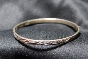 lot 63 image: Sterling Silver Taxco bangle bracelet. Marked  Mexico 925 Taxco with Eagle hallmark. Decorated with bas relief flowers and leaves. 19.0 gr approx