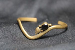 lot 91 image: Signed Navajo style brass cuff bracelet with Black Onyx center stone. Marked LORI inside.