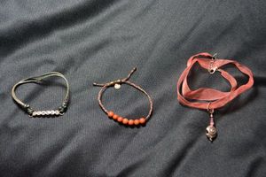 lot 129 image: (3) Ribbon necklace with Sterling Silver clasp (marked 925) with nautilus shell pendant. Necklace is 16L with 2 extender. Includes a signed Alex and Ani Carnelian ball tension bracelet (marked 925)and PEACE leather bracelet (marked 925 .