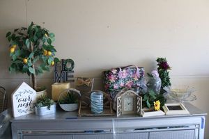 lot 85 image: Home decor artificial plants, glass vases, candle holder, wooden shelves and desk clock