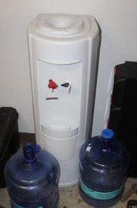 lot 21 image: Water dispenser with Hot and cold and 2 Empty 5 Gallon Bottles, This was being used by Consignor Until Recently