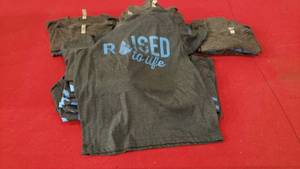 lot 202 image: Lot of 25 Raised To Life Shirts.  (YM 11, YL 4, LG 2, XL 6, XXL 2)