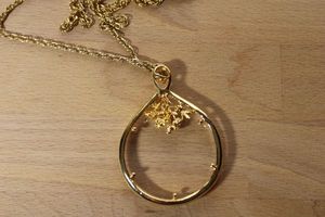 lot 102 image: Lorgnette Looking Glass (monoclemagnifier) 2.75L prong set pendant with floral frame decoration on a 30L chain. Spring ring clasp.