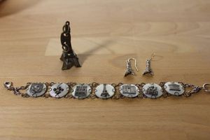 lot 103 image: Vintage Mother of Pearl Grand Tour Parisian souvenir panel bracelet. 8L. Features noted famous stops on Paris tour. Lobster clasp. Includes 2.5L Eiffel Tower purse dangle and Eiffel Tower ear wire earrings.