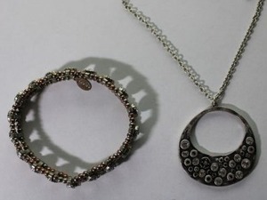 lot 111 image: Signed American Eagle Outfitters hammered metal and crystal pendant necklace on a 30L chain. Has AEO hang tag. Includes a two-tone crystal stretch bracelet with AEO hang tag.