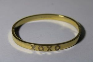 lot 130 image: Signed Ciao XOXO (AJNA Designs) Nicole Collection hinged gold tone stainless steel and CZ bangle. Marked SS 316L Tarnish Resistant (see httpsajnadesigns.combraceletsciaoxoxo-bj5yf)