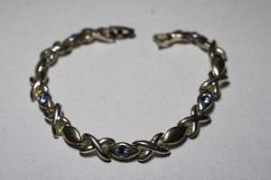 lot 187 image: Signed JJI (Jemco Jewelry Inc, 1980 - ) X and O silver plate bracelet with blue faceted crystals. 7L Fold over clasp.