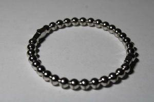 lot 196 image: Signed Kate Spade silver tone ball bead hinged bangle bracelet with push button catch. Marked Kate Spade New York on push button.