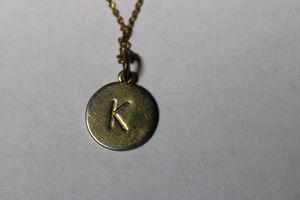lot 198 image: Signed Kate Spade One In A Million letter K pendant necklace. Marked Kate Spade New York on hang tag. 18L with 2 extender. Some loss to plating around edge of pendant