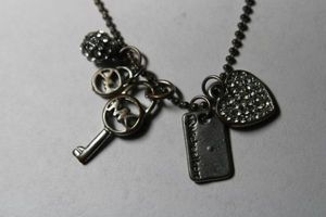 lot 273 image: Signed Michael Kors key and heart dangle ball bead necklace. Has Michael Kors hang tag. 18L with 2 extender.