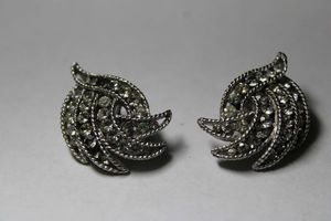 lot 305 image: Signed Crown Trifari (mark used 1955-1969) clip-on earrings in palm leaf form rhinestone crystals set within textured golden metal borders. Marked Trifari on reverse with crown. 1.25L. Has anti-tarnish Trifarium.
