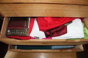 lot 11 image: Contents of cabinet - tablecloths, placemats, and candles