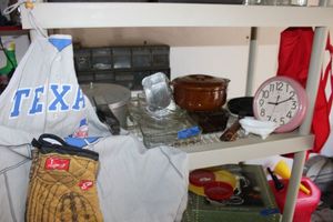 lot 323 image: Texas Rangers apron, pressure cooker, Pyrex baking dishes, crepe pan, brown pottery bowl, and Avon glass bathtub