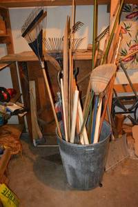 lot 217 image: Metal trash can with rakes, PVC pipe, and brooms