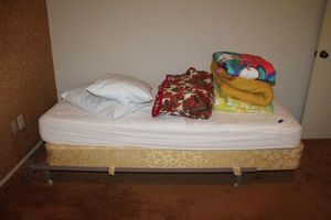 lot 142 image: Twin size bed frame with blankets and pillows