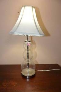 lot 111 image: UNIQUE CLEAR GLASS TABLE LAMP WITH WHITE SHADE