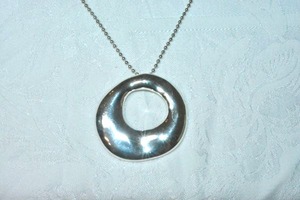 lot 69 image: Signed ATI freeform polished modernist donut disc pendant on ball bead 24L chain. Marked ATI BR on reverse. Rhodium finish. Pendant 2W x 2.25L