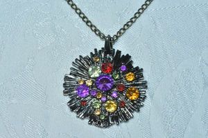 lot 79 image: Modernist black starburst shaped pendant with crystal accents on a 30L necklace. Lobster clasp. Pendant 2W