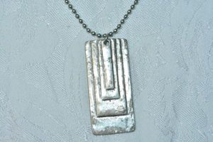 lot 83 image: Modernist art deco style long pendant with stepped design on a 24L ball bead chain. Pendant is 2L