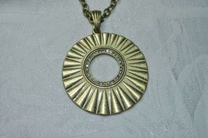 lot 139 image: Signed Lia Sophia ivory enamel modernist sundial pendant on 30L necklace. Has Lia Sophia hang tag. Lobster clasp. Pendant 3L